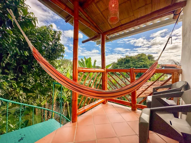 A hammock on the balcony of a room at Donkey Sunrise, looking over the valley