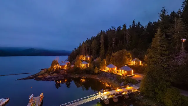 Luxury cedar yurts lit at dusk, Moutcha Bay Resort