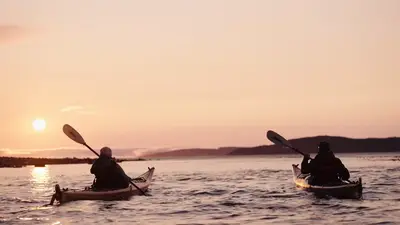 Sea kayakers paddling toward the setting sun