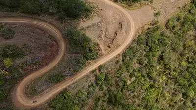 A dirt hairpin cut into the hillside, from the air