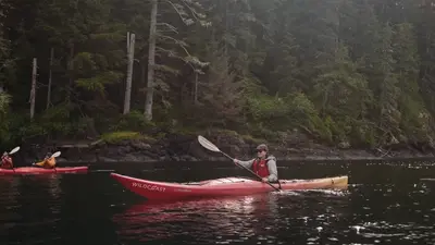 Two sea kayakers paddling out from camp
