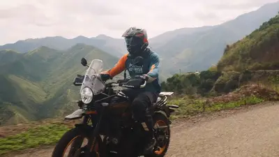 A rider on a Himalayan 450 on a ridge above the valley